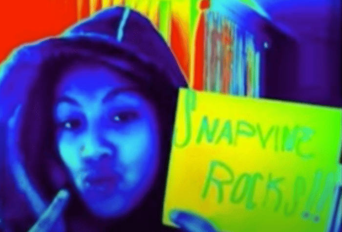A person wearing a hooded sweatshirt holds up a sign.. Text: SNAPVINE
ROCKS!!!