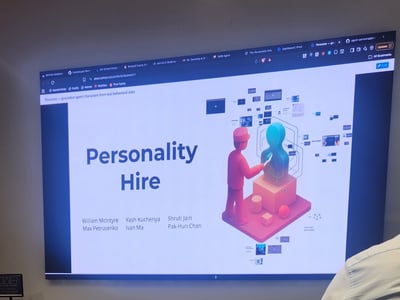 A photograph showing a large screen displaying a Prezi presentation titled 'Personality Hire' inside a web browser.