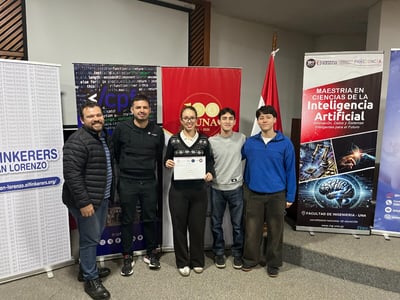A group of five people poses for a photo in front of several banners at an event related to Artificial Intelligence, with one person holding a certificate.
