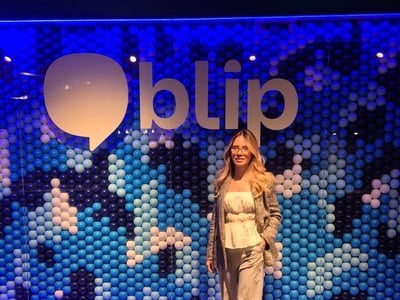 A woman stands and poses in front of a decorative wall made of blue and white balls, featuring a large 'blip' logo.