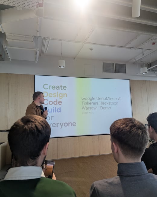 A man is giving a presentation at a Google DeepMind x AI Tinkerers Hackathon in Warsaw, standing in front of a large screen with an audience in the foreground.