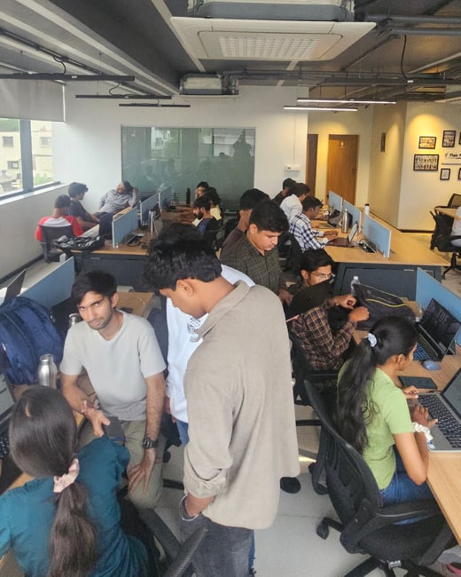 A group of young professionals are working and collaborating in a modern office setting with desks and laptops.