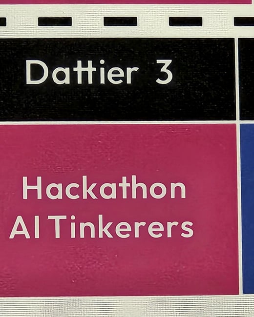 A close-up photograph captures a section of an event schedule or informational sign, displaying white text on alternating black and magenta colored blocks.