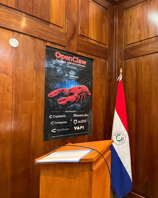 A photograph of a wood-paneled room featuring a poster for the 'OpenClaw Global Unhackathon' in Asunción, placed next to a wooden lectern and the flag of Paraguay.