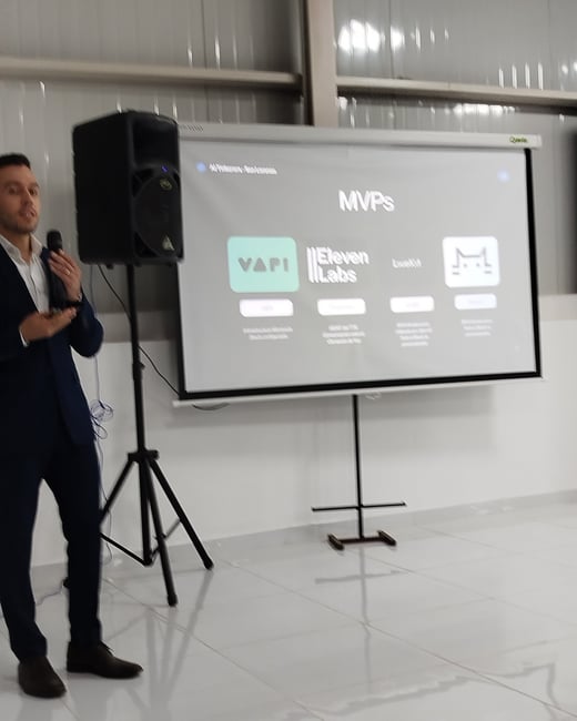 A man in a dark suit stands next to a projector screen presenting a slide titled 'MVPs' featuring logos for VAPI, Eleven Labs, and LiveKit.