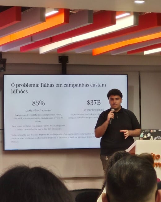 A man stands at a podium giving a presentation in front of a screen displaying statistics about marketing campaign failures in Portuguese.
