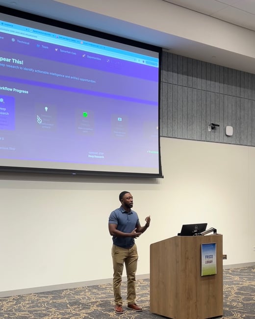 A man is giving a professional presentation indoors, standing next to a wooden podium labeled "Frisco Library," while a large projection screen behind him displays a technical workflow application with purple styling.