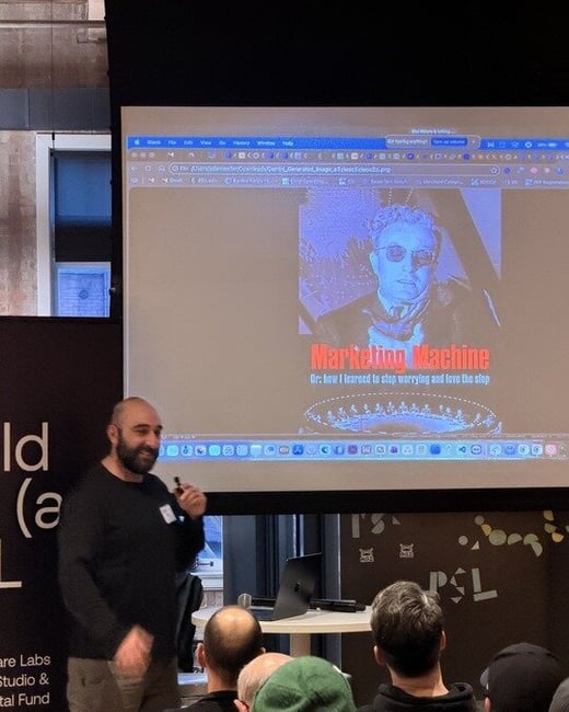 A man stands on a stage giving a presentation to an audience, with a large screen behind him displaying a slide titled 'Marketing Machine'.