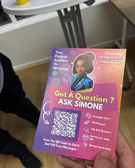 A close-up photograph shows a hand holding a vibrant, promotional flyer for a personal assistant service called "Simone," accessible via WhatsApp. The flyer features an illustration of a woman, a QR code, and details about the service's availability and features.