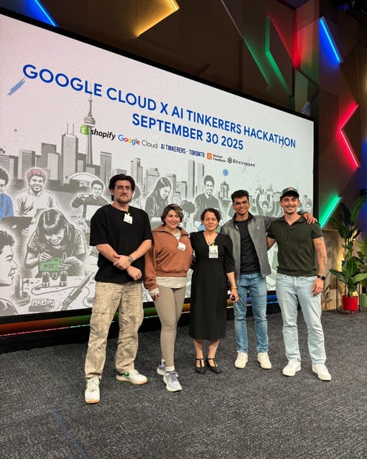 Five people, likely event participants or organizers, are posing for a group photo on a stage in front of a large screen displaying the title of the "Google Cloud x AI Tinkerers Hackathon."
