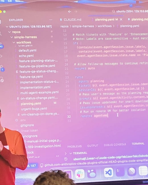 A photograph showing a presentation screen displaying code in the Visual Studio Code editor, with people in the foreground attending the session.