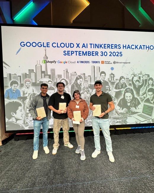 A photograph capturing four individuals (three men and one woman) standing on a stage, holding certificates or awards, in front of a large screen displaying information for the 'GOOGLE CLOUD X AI TINKERERS HACKATHO' event. The screen also features sponsor logos and a stylized black-and-white illustration of the Toronto skyline and diverse people working in technology.
