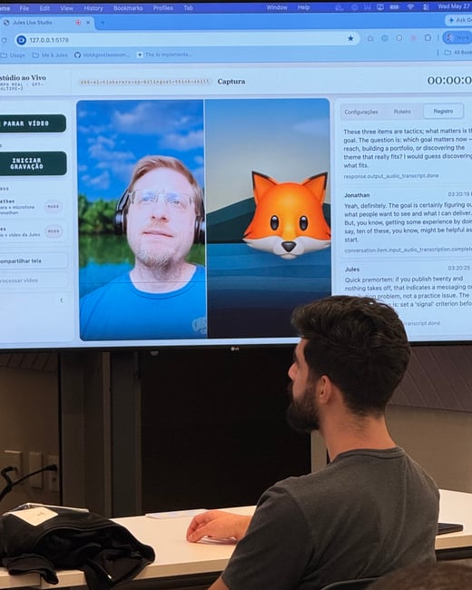 A man sits in an indoor room, looking up at a large monitor displaying a video call or recording interface with a live video feed of a man on the left and a 3D fox avatar on the right alongside real-time transcription text.