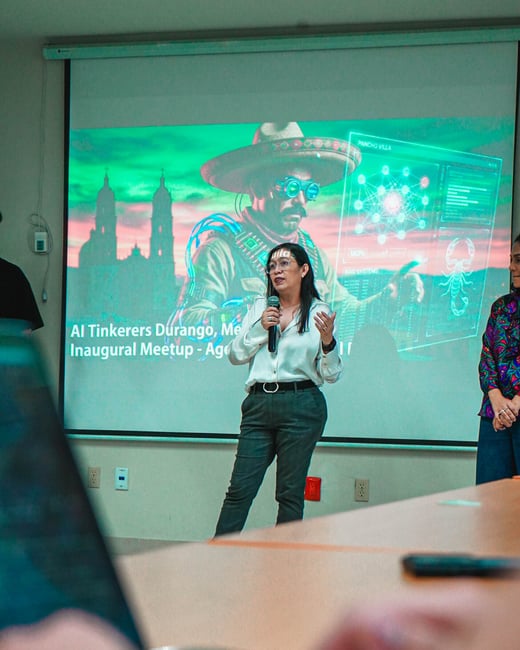 A woman stands in front of a projection screen giving a presentation at an AI Tinkerers meetup in Durango, Mexico.