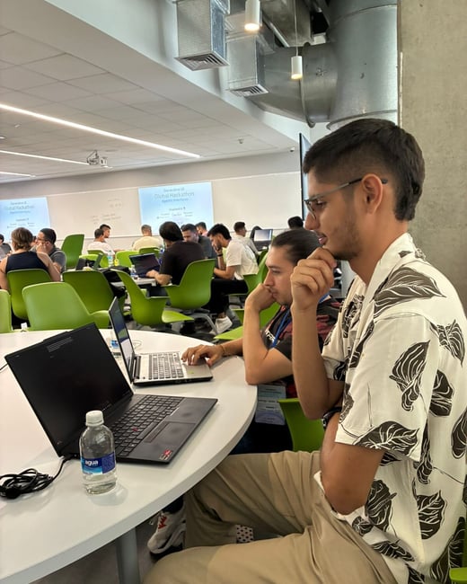 A group of people participating in a 'Generative UI Global Hackathon' inside a modern workspace, with individuals focused on their laptops at round tables.
