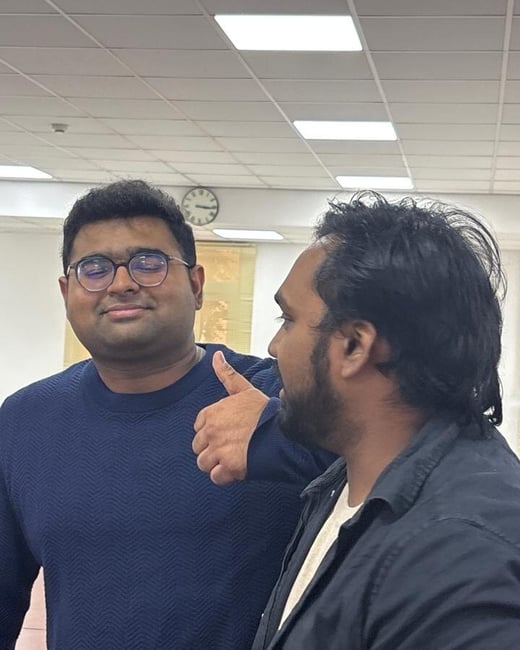 A photo of two men indoors, with one giving a thumbs-up gesture and a GPS location overlay at the bottom.