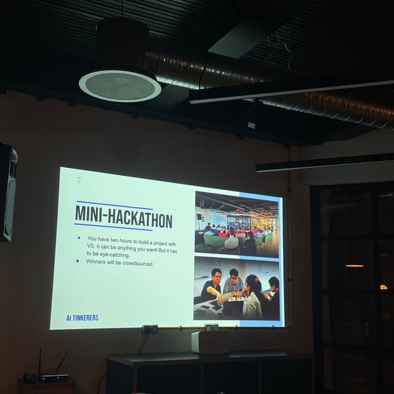 A photograph showing a projected presentation slide in a dimly lit indoor venue, detailing the rules for a "MINI-HACKATHON" event, including two embedded images of people participating in similar activities.