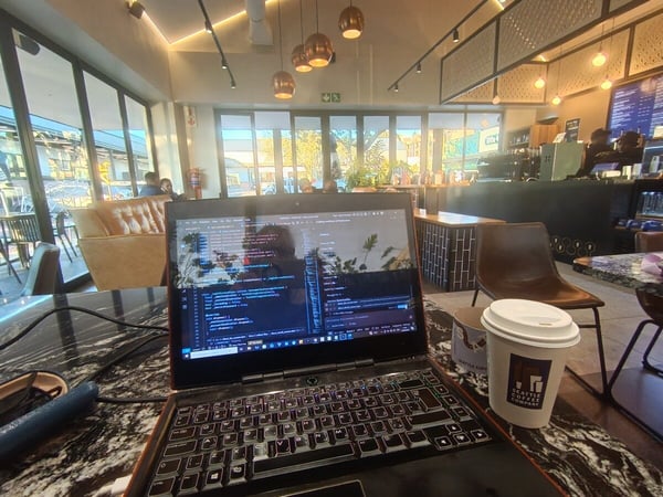 A first-person perspective shot of a person working on a laptop in a modern cafe, with a cup of coffee from Seattle Coffee Company on a marble table.