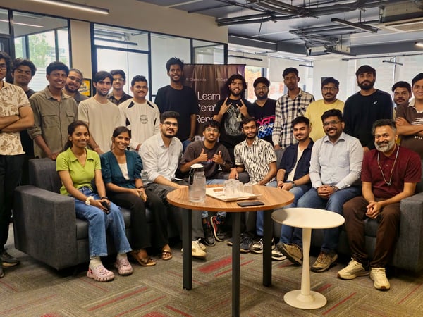 A group of approximately 25 people posing for a group photograph in a modern office lounge area.