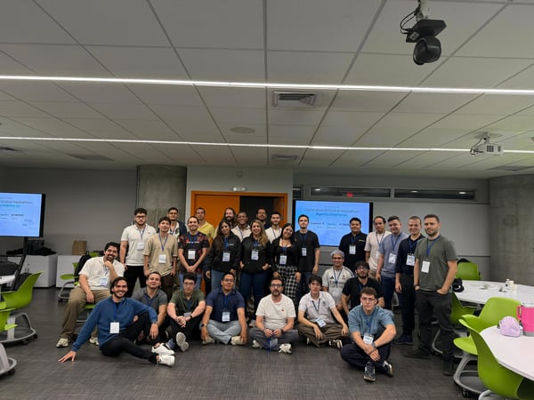A group of approximately 26 people posing for a group photo in a modern indoor space, likely following a hackathon event.