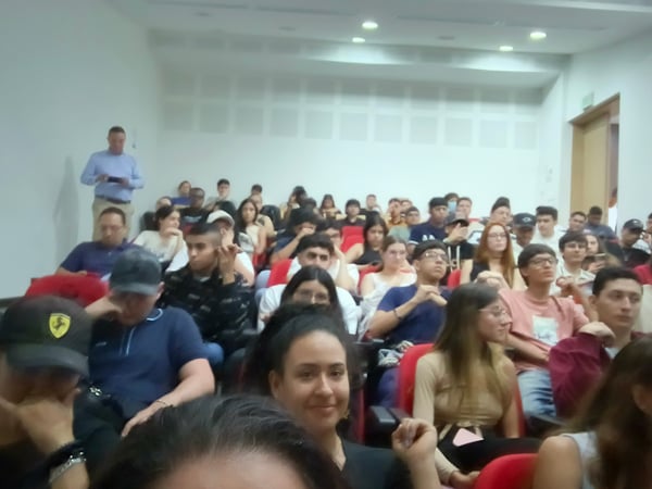 A photograph showing a large group of young adults seated in an auditorium, likely attending a lecture or presentation.