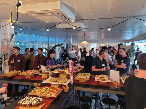 A group of people gathering around a large buffet table with various appetizers at an indoor social event.