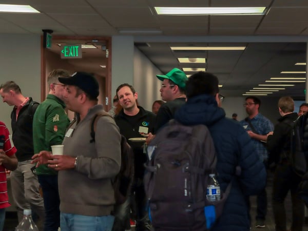 A group of people are gathered in an indoor hallway or common area, appearing to socialize during a break or event.