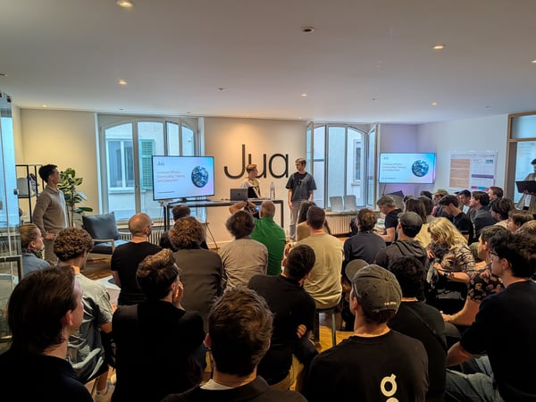 A group of people are gathered in a modern office space for a technical presentation by a company called Jua.