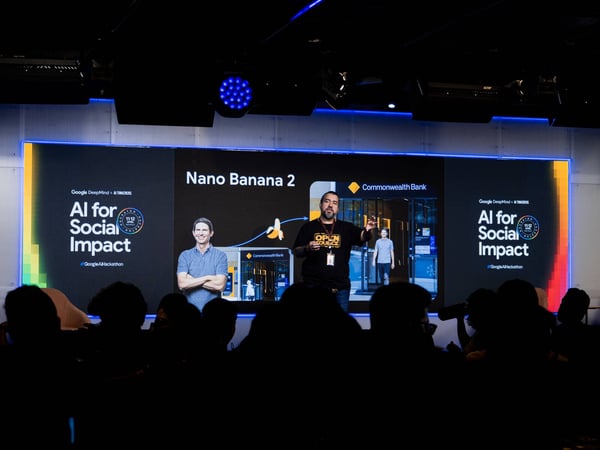 A man is giving a presentation on a stage titled 'AI for Social Impact' in front of a silhouetted audience.