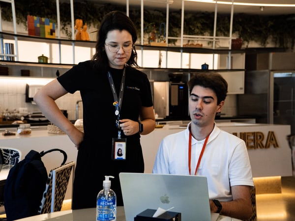 A woman and a man are collaborating over a laptop in a modern office or cafe environment.