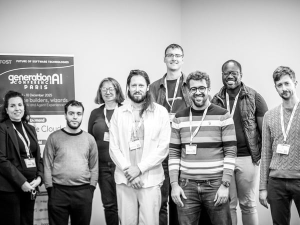 A black and white photograph shows a group of eight professionals, likely attendees or organizers of a conference, posing together indoors against a plain wall, with a 'generationAI' event banner visible on the left.