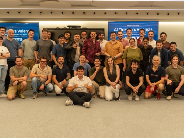 A large group of people posing for a commemorative photo at an 'AI Tinkerers Valencia' meetup event.