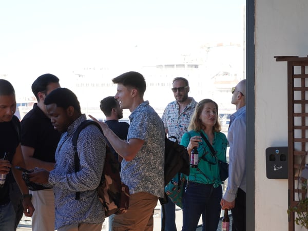 A group of people standing outside and socializing during a daytime gathering.