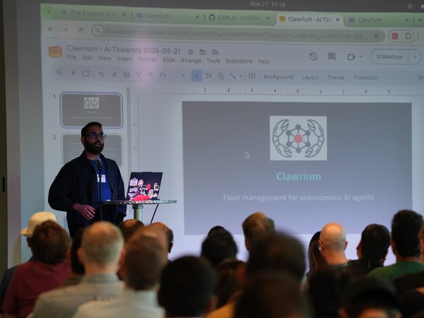 A man stands at a podium presenting a slide deck titled 'Clawrium - Fleet management for autonomous AI agents' to an audience at an AI Tinkerers event.