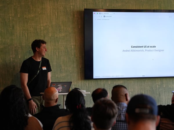 A man stands indoors presenting a slide deck titled 'Consistent UI at scale' to an audience.