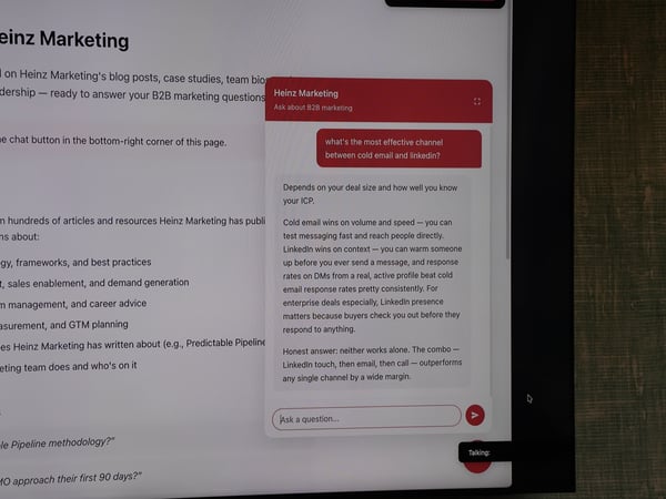A photograph of a computer monitor displaying a website with an active chat assistant widget discussing B2B marketing strategies.
