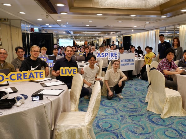 A group of people are gathered in a conference room for an event, posing for a group photo while holding various motivational signs.