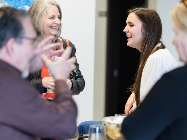 A group of people are engaged in a lively conversation during an indoor social gathering or event.