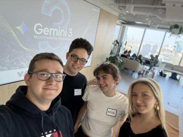 A group of four young people taking a selfie in a modern office, with a screen in the background displaying 'Gemini 3 Multimodality Hackathon'.
