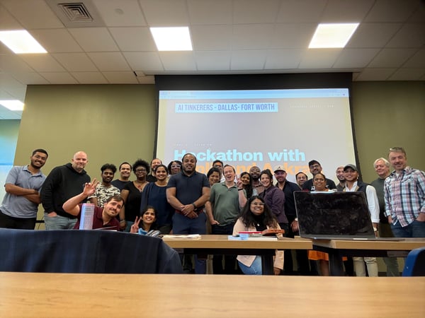 A diverse group of people posing for a group photograph in a conference room after an AI Tinkerers hackathon event.