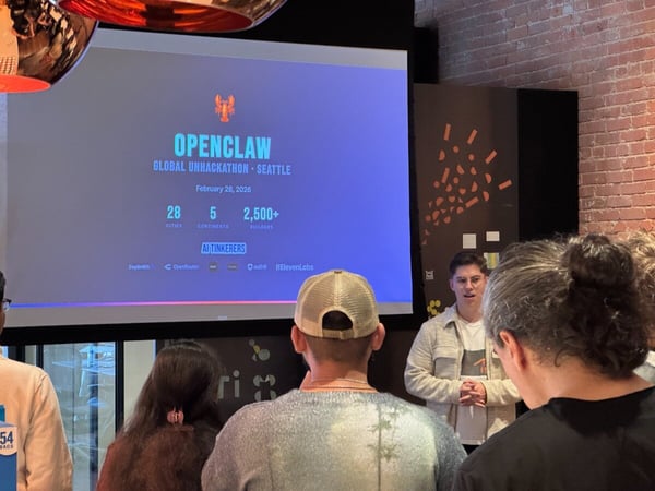 A photograph of a live presentation for 'OPENCLAW GLOBAL UNHACKATHON' in Seattle, featuring a speaker standing next to a large screen and an audience in the foreground.