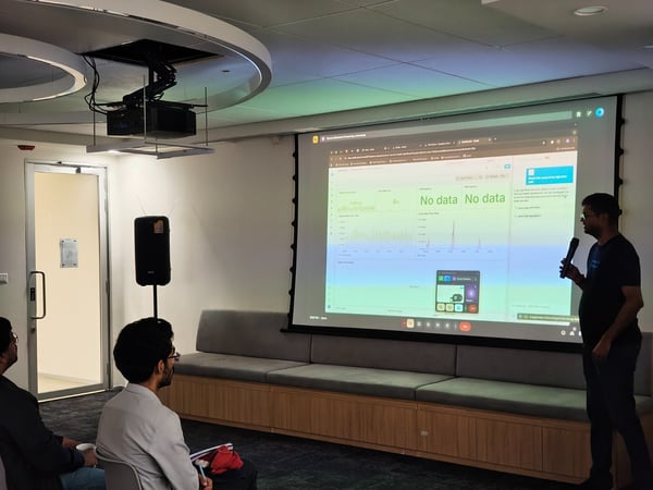 A man is giving a business presentation in a modern office meeting room, standing next to a large projection screen displaying a data dashboard that prominently features the text "No data."