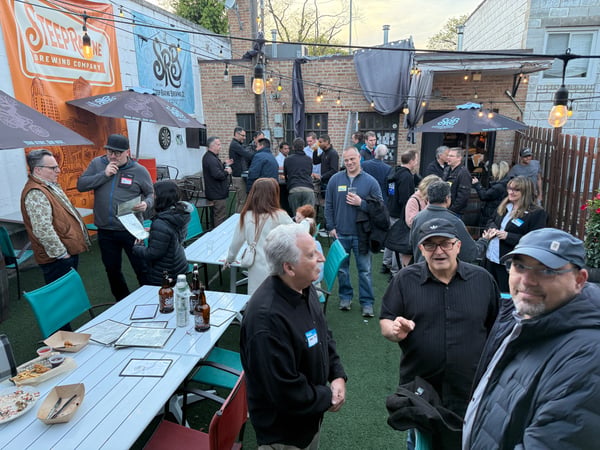 A group of people are socializing at an outdoor patio of the Steep Ravine Brewing Company, with tables, drinks, and string lights visible.