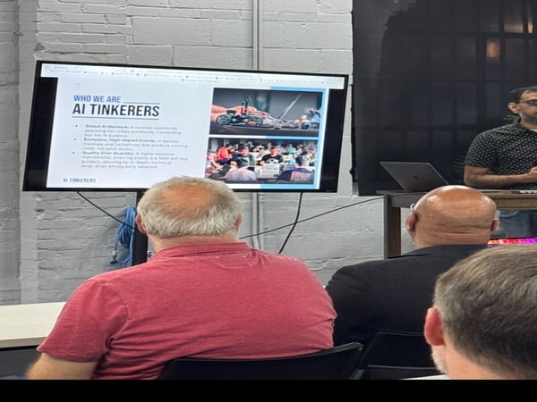 A group of people are attending a presentation where a screen displays information about 'AI TINKERERS', a community for AI builders.