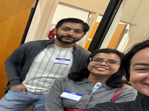 A group selfie of three people, two women and one man, wearing name tags in an indoor setting. The image is oriented horizontally.