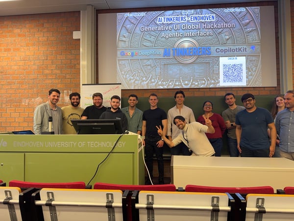A group of people posing for a photo in a lecture hall at Eindhoven University of Technology, standing in front of a presentation screen for an AI hackathon.