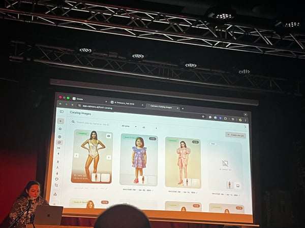 A woman is giving a presentation on a stage, with a large screen behind her displaying a web application for managing catalog images.