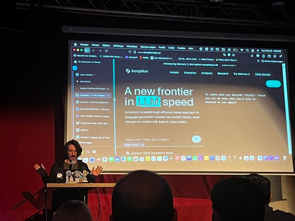 A man is standing on a stage giving a presentation in front of a large screen displaying the 'Inception' website about LLM speed.