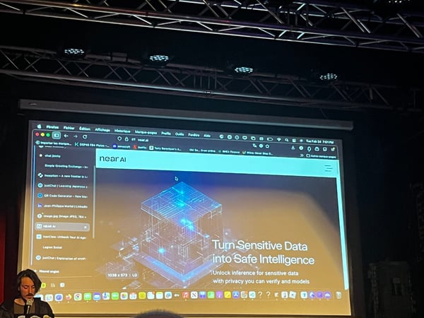 A man is giving a presentation in a dark room, with a large projection screen behind him displaying a website for 'near AI'.