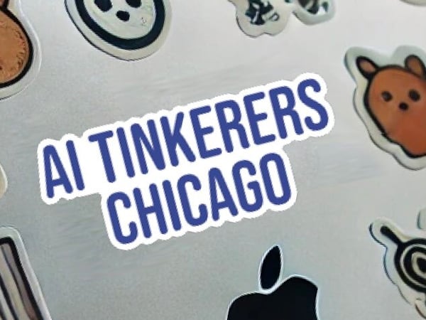 A close-up photograph of a collection of stickers and magnets affixed to a metallic surface, featuring a prominent blue and white sticker that reads 'AI TINKERERS CHICAGO'.